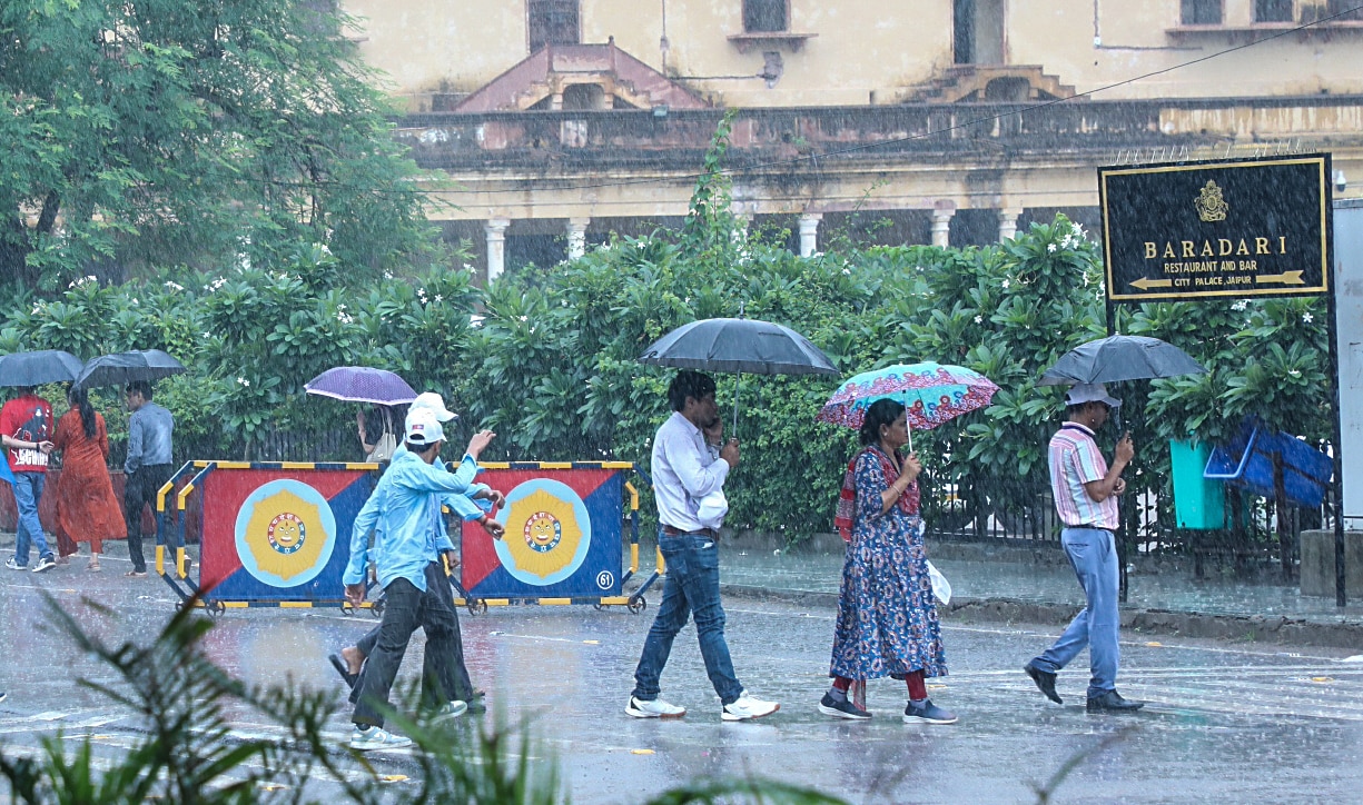 People holding umbrellas cross road amid heavy rain, in Jaipur on Saturday. (ANI) People holding umbrellas cross road amid heavy rain, in Jaipur on Saturday. (ANI)