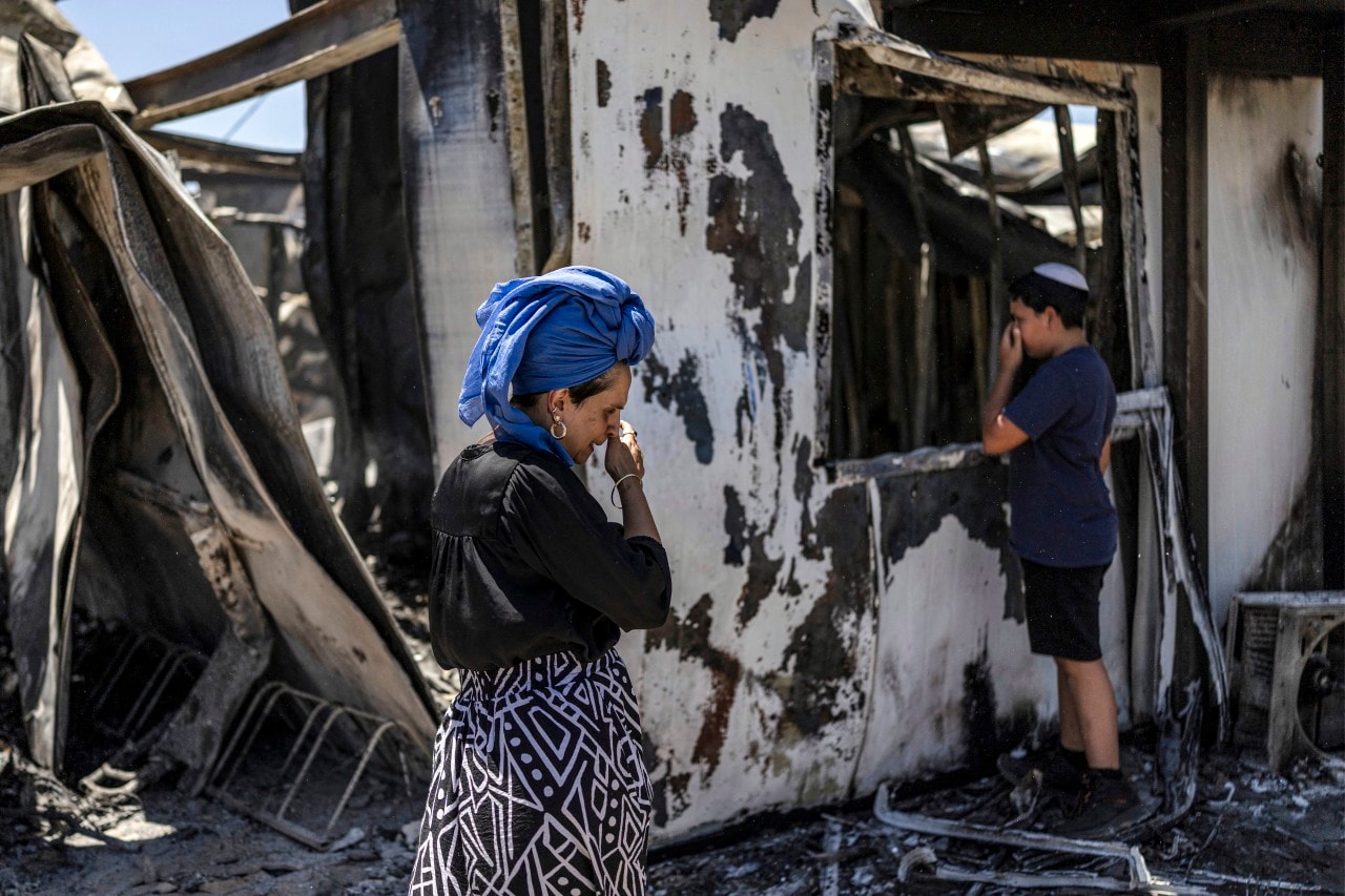 Israeli settlers at the remains of their house in the Havat Gilad settlement on July 19, the day after it burned.