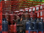 A delivery worker stands atop a truck carrying LPG cylinders at a HP Gas distribution point in Bengaluru.