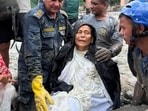 Nepal Police officers assist Chandika Kumari Shrestha after she was rescued alive from a damaged house following deadly flash floods and mudslides, in Betrawati in Nuwakot district, Nepal.