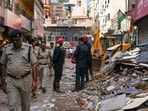 Rescue personnel stand near debris during a rescue operation on the second day after a 50-year-old five-storey building housing a boys' hostel collapsed in a congested bylane in Satya Niketan near Delhi University's south campus
