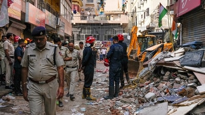 Rescue personnel stand near debris during a rescue operation on the second day after a 50-year-old five-storey building housing a boys' hostel collapsed in a congested bylane in Satya Niketan near Delhi University's south campus (PTI) Rescue personnel stand near debris during a rescue operation on the second day after a 50-year-old five-storey building housing a boys' hostel collapsed in a congested bylane in Satya Niketan near Delhi University's south campus (PTI)