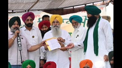 Punjab agriculture minister Gurmeet Singh Khudian hands over an assurance letter to farmer leaders at their protest site in Mohali on Monday. (Ravi Kumar/HT)