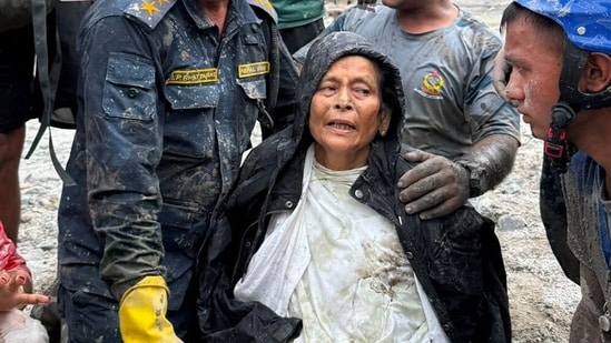 Nepal Police officers assist Chandika Kumari Shrestha after she was rescued alive from a damaged house following deadly flash floods and mudslides, in Betrawati in Nuwakot district, Nepal.