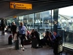 People sit on the floor with their luggage inside Terminal 5 of London Heathrow Airport, west of London, on September 8, 2026, following major disruption.