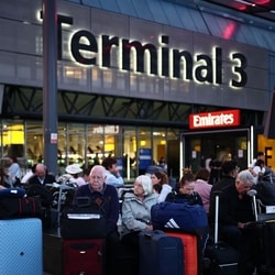 Passengers sit with their luggage outside Terminal 3 of London Heathrow airport, west of London.
