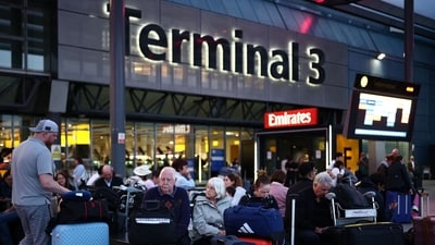 Passengers sit with their luggage outside Terminal 3 of London Heathrow airport, west of London. (AFP)