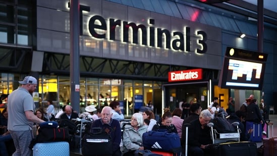 Passengers sit with their luggage outside Terminal 3 of London Heathrow airport, west of London. (AFP)