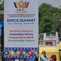 Pedestrians wait at a bus stand near a hoarding, displayed ahead of the BRICS summit in New Delhi on September 9, 2026. (Photo by Sajjad HUSSAIN / AFP)