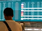 A stranded passenger looks at a flight information screen.