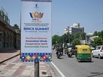 Traffic moves along a street past a hoarding, displayed ahead of the BRICS summit in New Delhi on September 9, 2026. (Photo by Sajjad HUSSAIN / AFP)