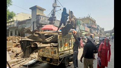 Workers carry corrugated metal sheets from the demolished site during an ongoing infrastructure development and road-widening project near the Nai Basti area, in Jammu on Thursday. (ANI)