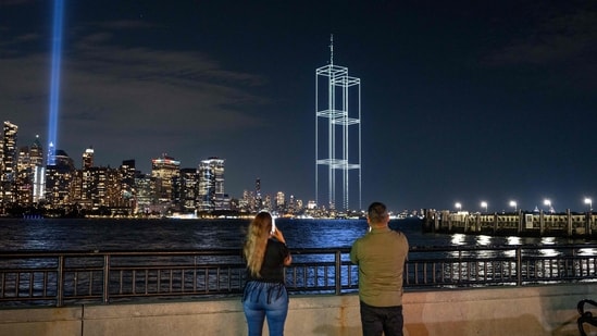 People watch and take pictures as a drone light show depicting the twin towers appears in the skyline during testing of Tribute in Light installation in lower Manhattan on September 9, 2026, as seen from Liberty State Park in Jersey City, New Jersey. The twin beams shine from dusk on September 11 until dawn on September 12 every year. Jeremy Weine/Getty Images/AFP (Photo by Jeremy Weine / GETTY IMAGES NORTH AMERICA / Getty Images via AFP)