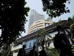 Men walk past a screen displaying market results outside the Bombay Stock Exchange (BSE) in Mumbai, India
