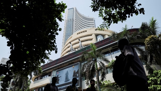 Men walk past a screen displaying market results outside the Bombay Stock Exchange (BSE) in Mumbai, India