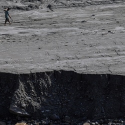 A man walks along a mud-covered riverbank following deadly flash floods and mudslides, in Dhading district, Nepal, September 14, 2026.