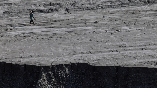 A man walks along a mud-covered riverbank following deadly flash floods and mudslides, in Dhading district, Nepal, September 14, 2026.