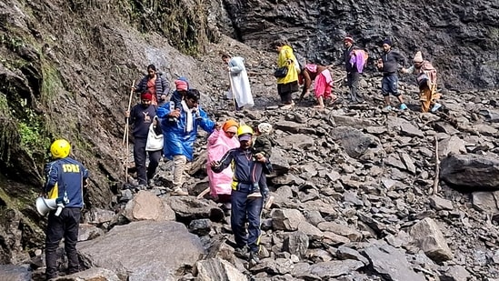 SDRF personnel evacuate stranded pilgrims after debris and stones temporarily closed the Kedarnath Yatra trekking route near Chirbasa helipad, in Rudraprayag. (PTI)