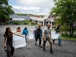 Director Alex Myers, in gray shirt, leads a group of students across campus to harvest corn. Most of the school’s classes take place in the red buildings.