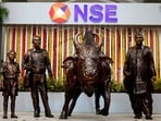 Stock market Sep 17: Statues of people and a bull are seen next to the logo of the National Stock Exchange (NSE) in Mumbai