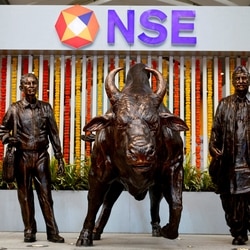 NSE IPO LIVE updates: Statues of people and a bull are seen next to the logo of the National Stock Exchange (NSE) in Mumbai
