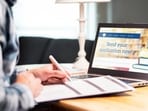Young man writing college or university application form with pen and paper. Student applying or filling document. Scholarship, grant or admission. School website in laptop. (Getty Images/iStockphoto)