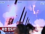 People sit near a television screen showing a news broadcast with file footage of a North Korean missile test at a train station in Seoul. 