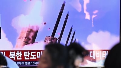 People sit near a television screen showing a news broadcast with file footage of a North Korean missile test at a train station in Seoul. (AFP)
