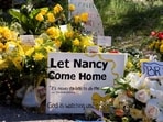 FILE PHOTO: A sign reads stands amid yellow flowers left at the house of Nancy Guthrie, the 84-year-old mother of U.S. journalist and television host Savannah Guthrie, who went missing from her home on February 1, in Tucson, U.S., February 21, 2026.  REUTERS/Rebecca Noble/File Photo
