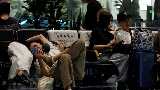 Passengers rest at Haneda Airport as many flights are delayed and cancelled due to Typhoon Dujuan, in Tokyo, Japan, September 21, 2026.