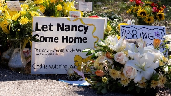 FILE PHOTO: A sign reads stands amid yellow flowers left at the house of Nancy Guthrie, the 84-year-old mother of U.S. journalist and television host Savannah Guthrie, who went missing from her home on February 1, in Tucson, U.S., February 21, 2026.  REUTERS/Rebecca Noble/File Photo