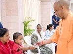 Chief minister Yogi Adityanath gives chocolate to a child during Janata Darshan, in Lucknow on Monday. (@CMOfficeUPX/ANI Photo)