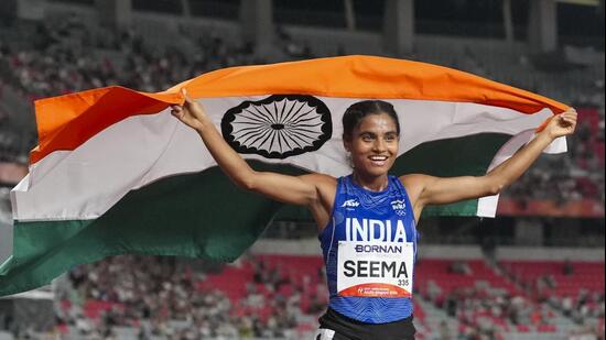 India’s Seema holds the national flag as she celebrates after winning the bronze medal in the women's 10,000m final during the Asian Games 2026. (PTI)