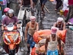 Porters haul goods on a handcart through a market street during rain triggered by a weather system over the Bay of Bengal.