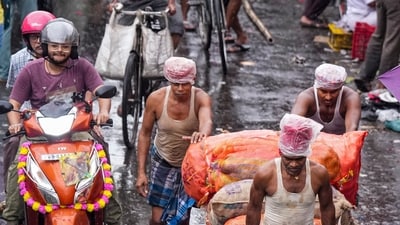 Porters haul goods on a handcart through a market street during rain triggered by a weather system over the Bay of Benga. (PTI) Porters haul goods on a handcart through a market street during rain triggered by a weather system over the Bay of Benga. (PTI)