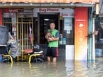 A man holding a small dog poses for a photo while standing in floodwaters in the Bang Bua district of Bangkok on September 26, 2026. 