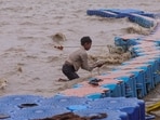 A boy searches for alms and valuables amid strong wind at the bank of Sangam, in Prayagraj, Uttar Pradesh, Saturday, Sept. 26. 