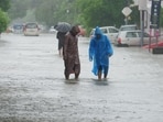People wading through a waterlogged road in Ashiana area of Lucknow on Saturday. (Deepak Gupta/HT Photo)