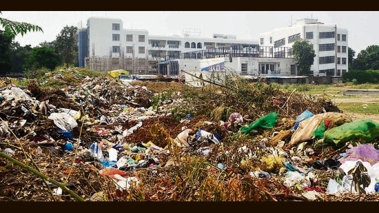 A heap of garbage dumped in a plot behind a private school in Ludhiana on Saturday. (Gurpreet Singh/HT)