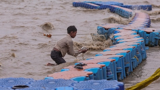 A boy searches for alms and valuables amid strong wind at the bank of Sangam, in Prayagraj, Uttar Pradesh, Saturday, Sept. 26.