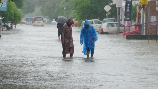 People wading through a waterlogged road in Ashiana area of Lucknow on Saturday. (Deepak Gupta/HT Photo)