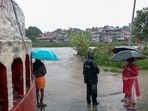 A view of local residents holding umbrellas and wearing raincoats as they watch the water level rise in the swollen Bagmati River following continuous downpours, in Kathmandu on Friday. (ANI Video Grab)