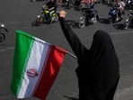 A woman chants slogan as she holds an Iranian flag while motorcyclists ride during a state-organized motorcycle parade called "Janfada," meaning "Sacrifice for Iran", in Tehran, Iran, Friday, Sept. 25, 2026. 
