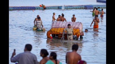 People carry their belongings to safer places along the banks of the Sangam as the water level rises following heavy rain, in Prayagraj, on Sunday (PTI)
