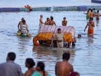 People carry their belongings to safer places along the banks of the Sangam as the water level rises following heavy rain, in Prayagraj, on Sunday (PTI)