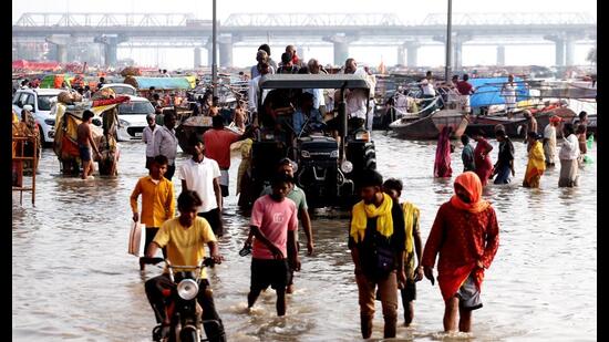 People carry their belongings to safer places along the banks of the Ganga river as the water level rises following heavy rain in Prayagraj on Monday (PTI)