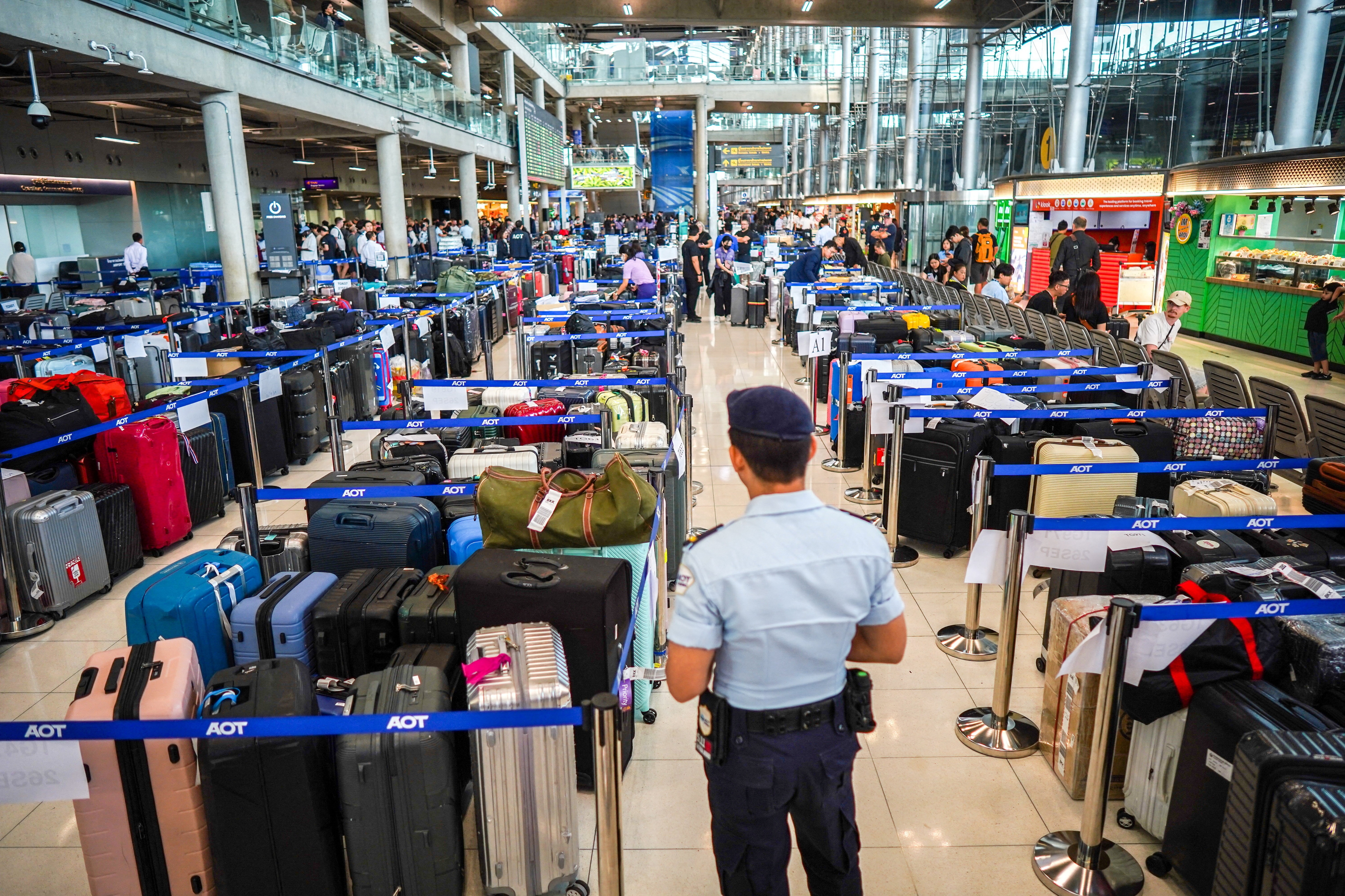 A member of airport security stands next to baggage from Thai Airways flights at Suvarnabhumi International Airport, after heavy rain and flooding disrupted the airline's ground operations, in Bangkok. (Reuters)