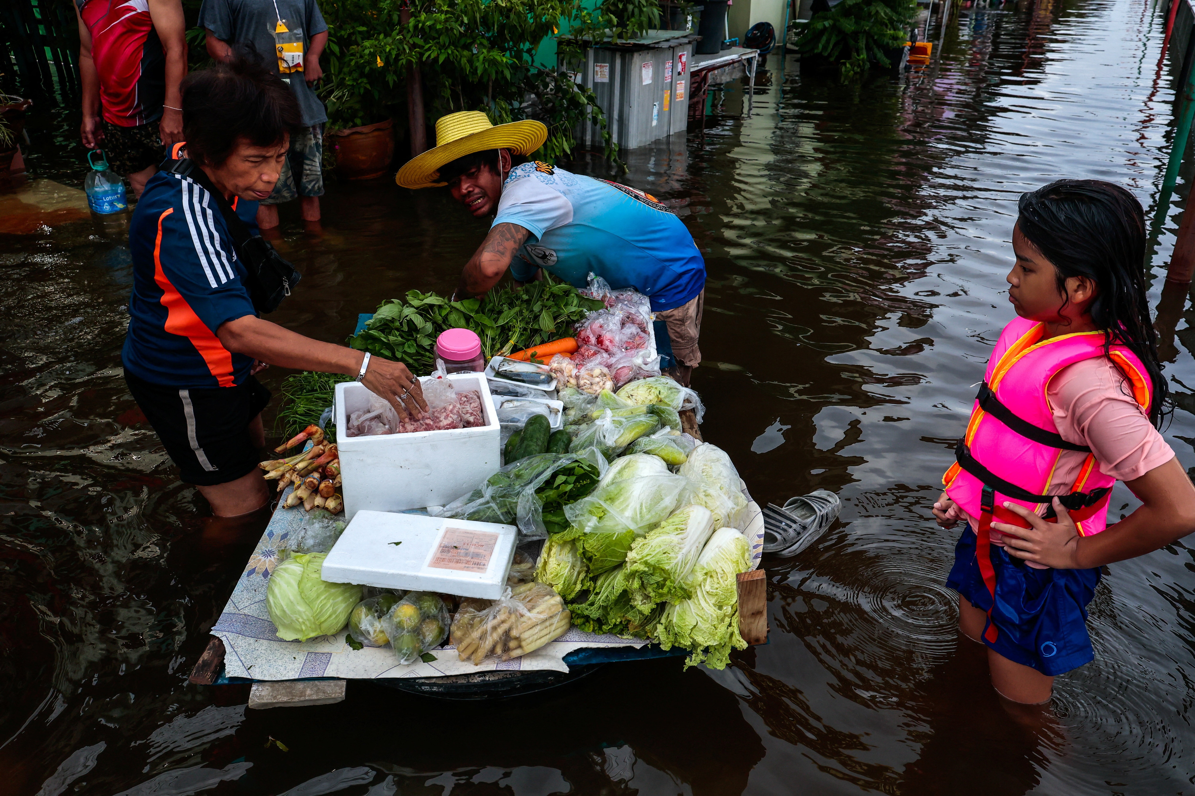 A woman shops for groceries on a floating platform in a flooded area following heavy rain in Bangkok. (File Photo/Reuters)