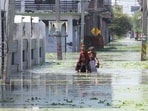 Residents wade through waist-deep water in the Mama Colony-Daudnagar area of Faizullaganj following a rise in Gomti river's level after days of incessant rainfall in Lucknow. (Deepak Gupta/HT Photo)