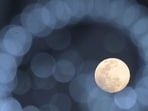 The Cold Moon is pictured behind Christmas decorations in Cali, Colombia on December 3, 2025. (Photo by JOAQUIN SARMIENTO / AFP)(AFP)